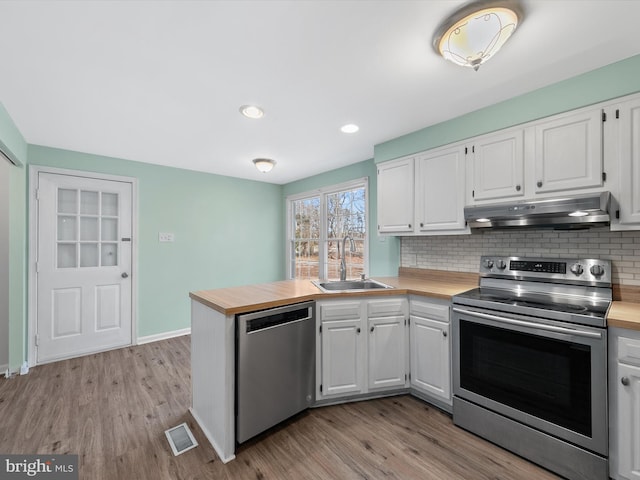 kitchen with backsplash, white cabinets, sink, light hardwood / wood-style flooring, and stainless steel appliances