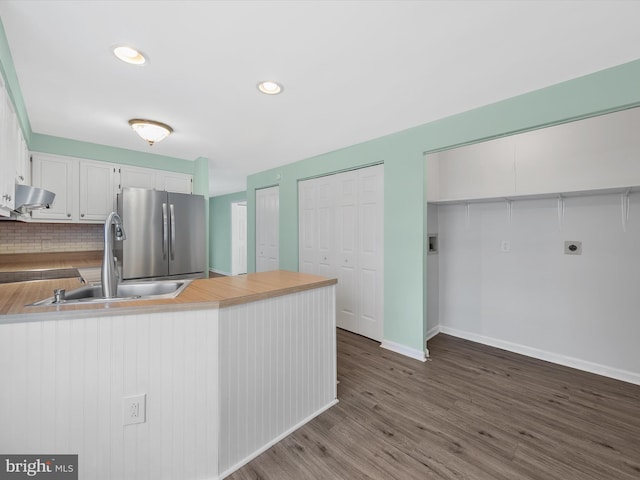 kitchen featuring stainless steel fridge, kitchen peninsula, sink, and white cabinetry