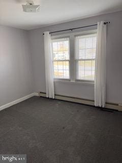 unfurnished room with dark colored carpet, a baseboard radiator, and plenty of natural light