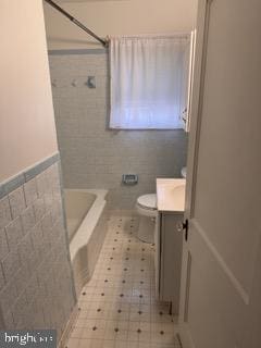 bathroom featuring tile patterned flooring, vanity, toilet, and tile walls