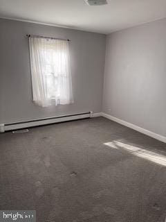 carpeted spare room featuring a baseboard heating unit