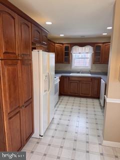 kitchen featuring range, white fridge with ice dispenser, and sink