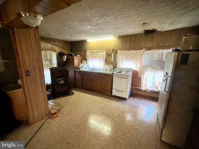 kitchen featuring a textured ceiling, white appliances, plenty of natural light, and wooden walls