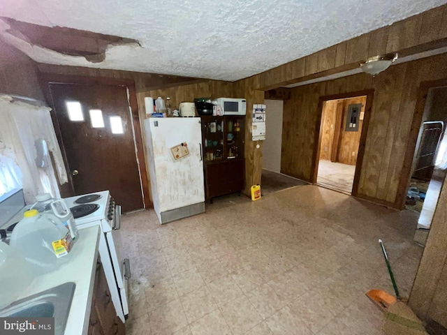 kitchen featuring a textured ceiling, white appliances, and wooden walls