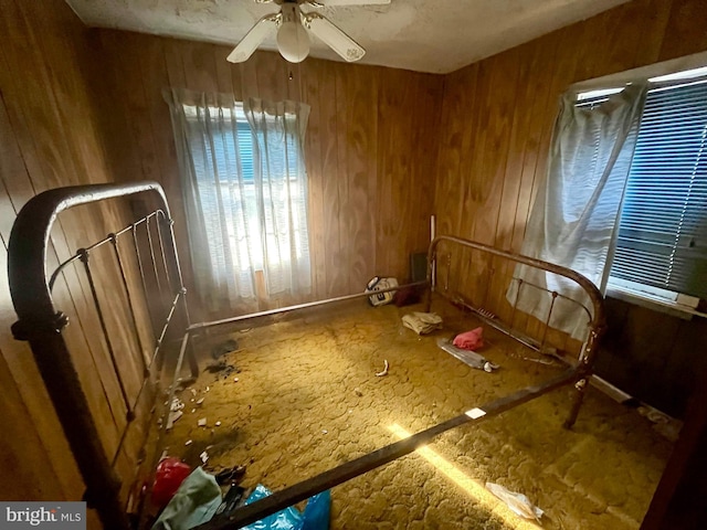 interior space with ceiling fan and wooden walls