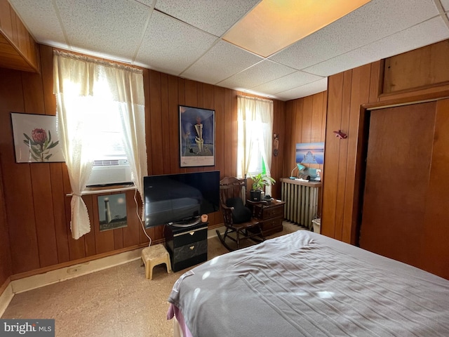 bedroom with a drop ceiling, wood walls, and cooling unit