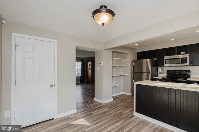 kitchen with light stone countertops, stainless steel appliances, and light hardwood / wood-style flooring