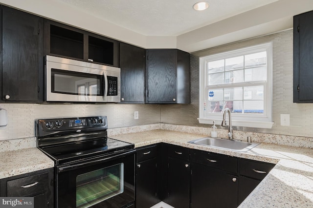 kitchen with decorative backsplash, light stone counters, black / electric stove, and sink