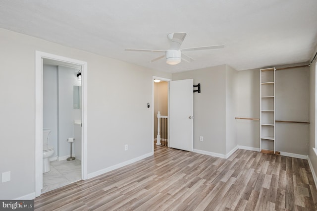 unfurnished bedroom featuring ceiling fan, light hardwood / wood-style floors, a spacious closet, and ensuite bath