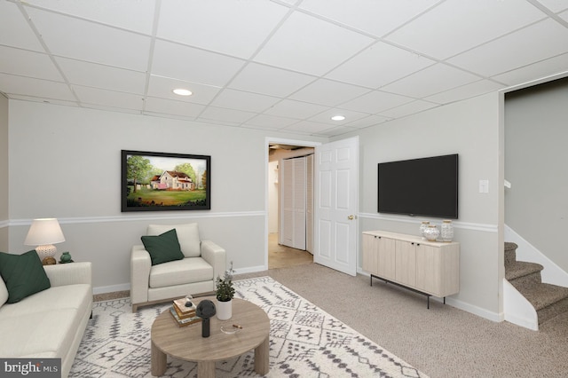 living room with a drop ceiling and light colored carpet