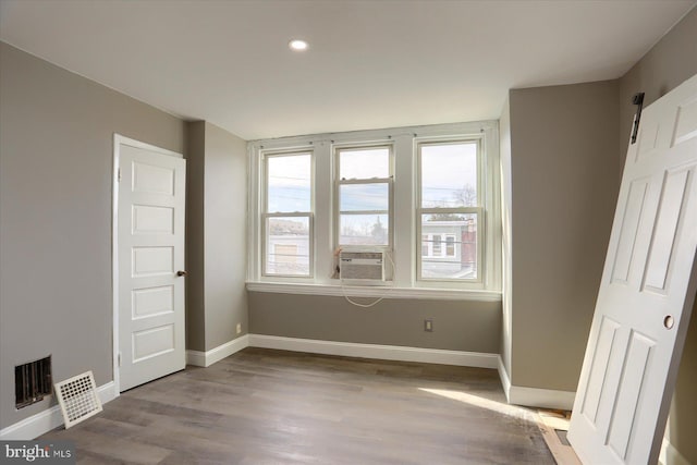 spare room with cooling unit, a barn door, and light hardwood / wood-style flooring