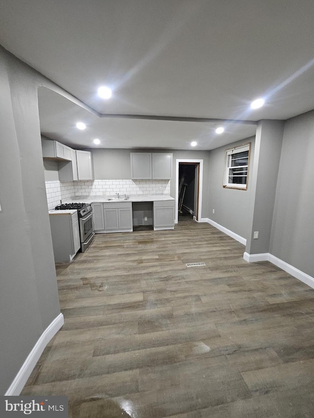 kitchen featuring gray cabinetry, sink, light hardwood / wood-style flooring, gas range, and tasteful backsplash