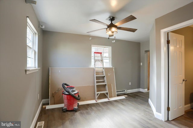 interior space featuring hardwood / wood-style floors, ceiling fan, and baseboard heating