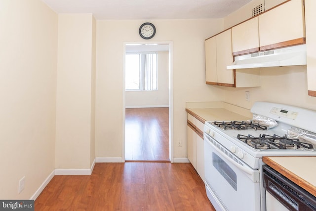 kitchen with dishwashing machine, white gas stove, white cabinets, and light hardwood / wood-style flooring