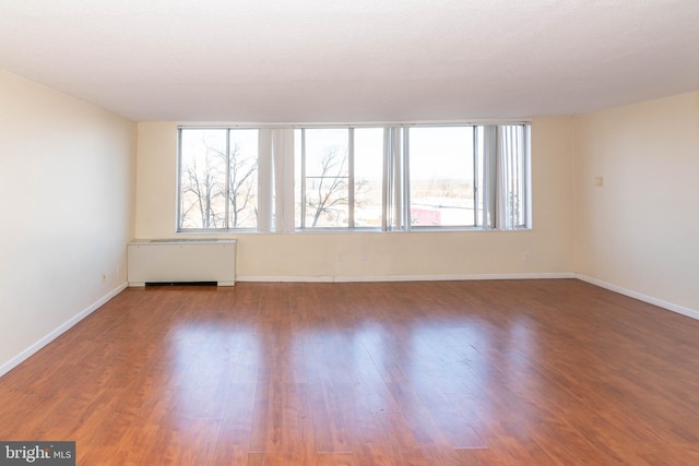 empty room featuring radiator and hardwood / wood-style flooring