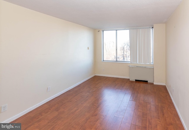 empty room featuring hardwood / wood-style flooring and radiator