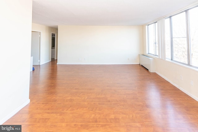 empty room with radiator heating unit and light hardwood / wood-style floors