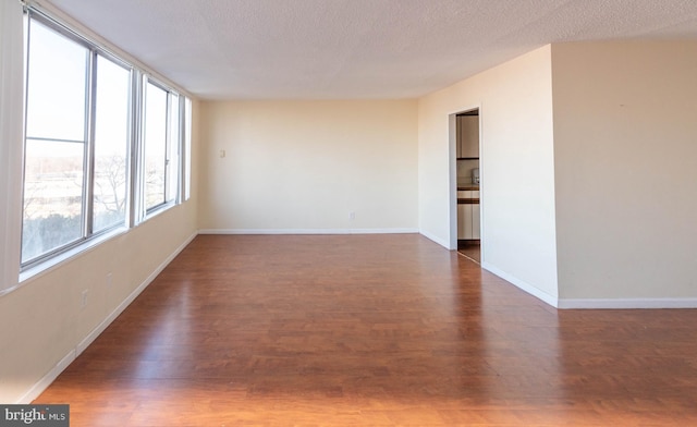 empty room featuring dark wood-type flooring and a textured ceiling