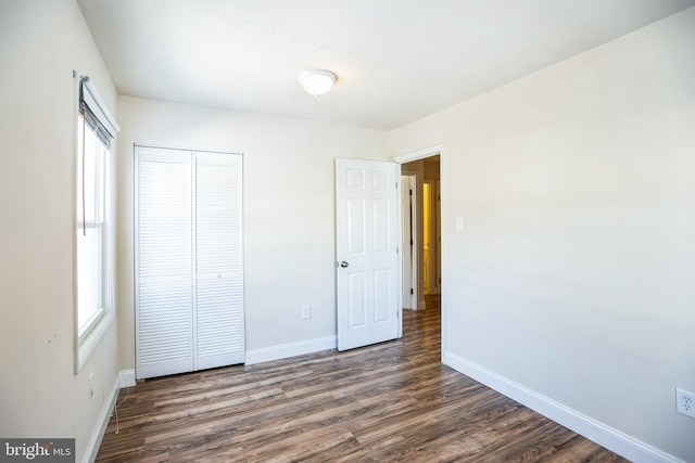 unfurnished bedroom with dark hardwood / wood-style flooring and a closet