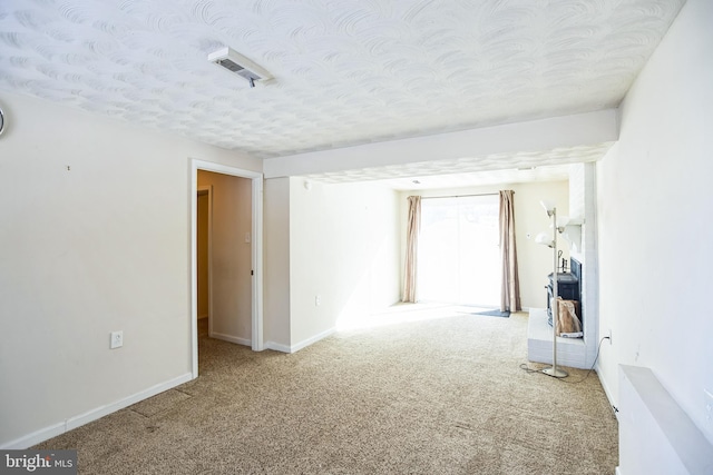 empty room with a textured ceiling and light carpet