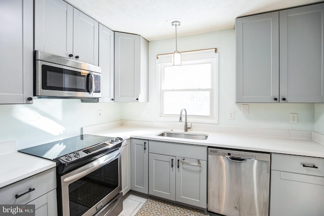 kitchen featuring pendant lighting, sink, gray cabinets, light tile patterned flooring, and stainless steel appliances