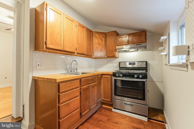 kitchen featuring dark hardwood / wood-style flooring, backsplash, stainless steel gas range, ceiling fan, and sink