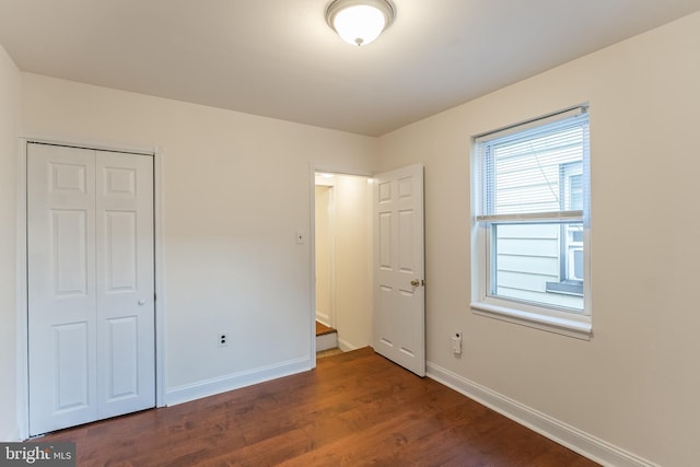 unfurnished bedroom featuring a closet and dark wood-type flooring