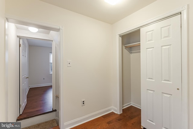 unfurnished bedroom with dark wood-type flooring and a closet