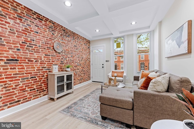 living room with beam ceiling, light wood-type flooring, coffered ceiling, and brick wall