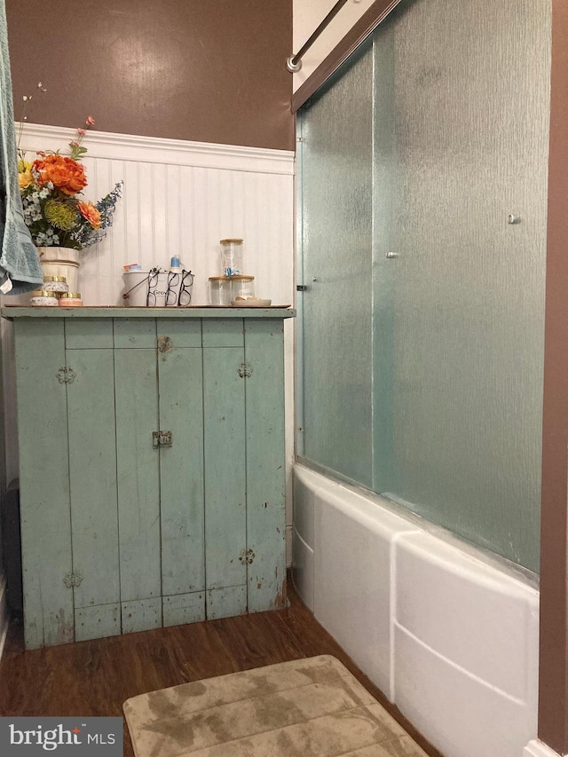 bathroom with wood-type flooring and shower / bath combination with glass door