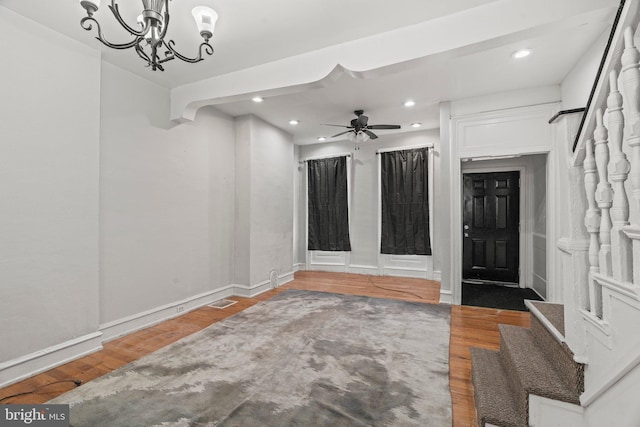 foyer entrance with hardwood / wood-style floors and ceiling fan with notable chandelier