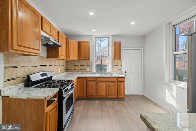 kitchen with tasteful backsplash, gas range, light hardwood / wood-style floors, and a textured ceiling