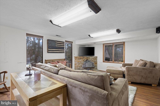 living room with hardwood / wood-style floors, a textured ceiling, and a wood stove