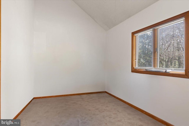 carpeted spare room with lofted ceiling