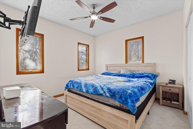 bedroom featuring light carpet, a textured ceiling, and ceiling fan