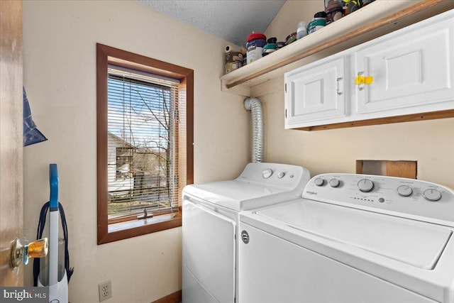 clothes washing area featuring washing machine and clothes dryer, cabinets, and a textured ceiling