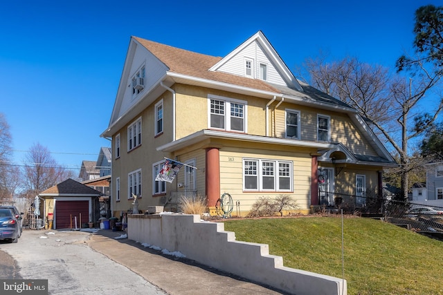 view of front facade featuring a garage, an outdoor structure, and a front lawn