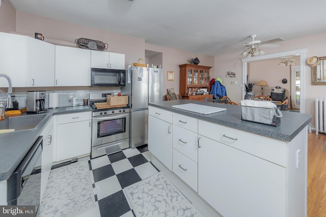 kitchen featuring sink, radiator heating unit, a center island, black appliances, and white cabinets