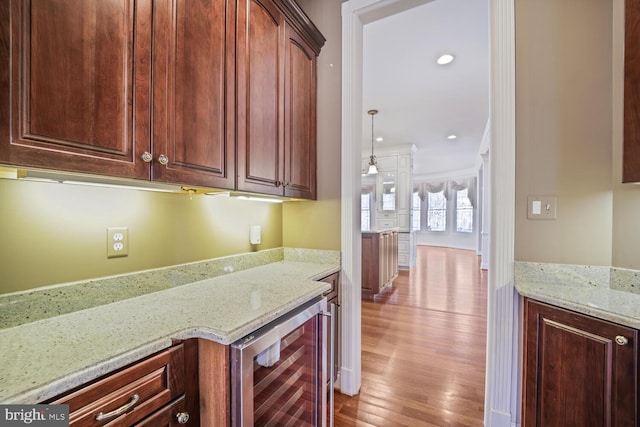 kitchen featuring wine cooler, light stone counters, decorative light fixtures, light wood-type flooring, and recessed lighting