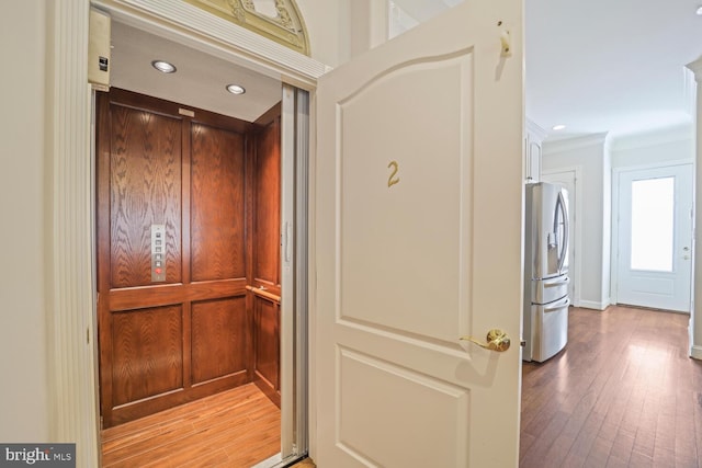 details featuring elevator, stainless steel refrigerator with ice dispenser, wood finished floors, and recessed lighting