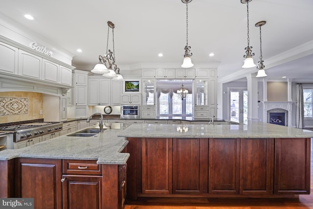 kitchen featuring white cabinetry, a sink, a large island, and light stone countertops