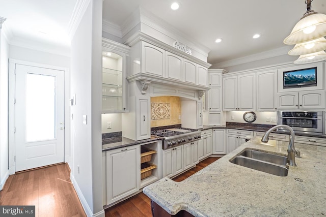 kitchen featuring stainless steel appliances, decorative light fixtures, a sink, and white cabinetry