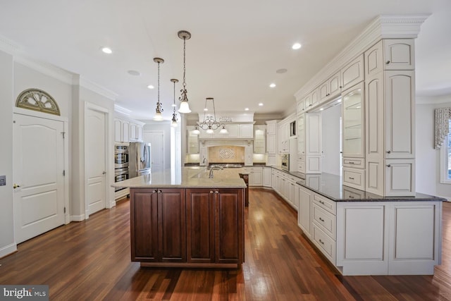 kitchen featuring an island with sink, dark stone counters, pendant lighting, and ornamental molding