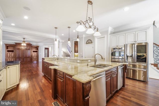 kitchen featuring appliances with stainless steel finishes, a sink, a large island with sink, and pendant lighting