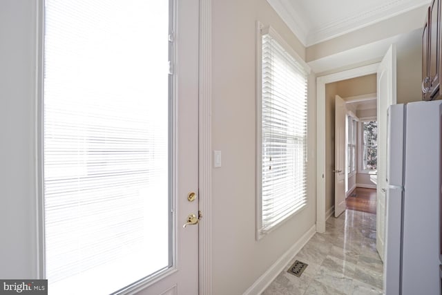 entryway with baseboards, visible vents, and crown molding