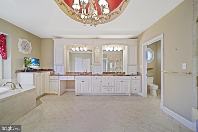 bathroom with a garden tub, toilet, a notable chandelier, baseboards, and double vanity