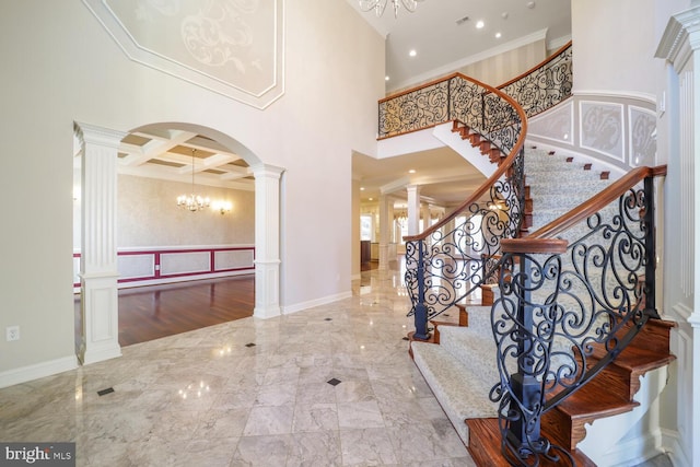 entrance foyer with arched walkways, marble finish floor, decorative columns, a towering ceiling, and coffered ceiling