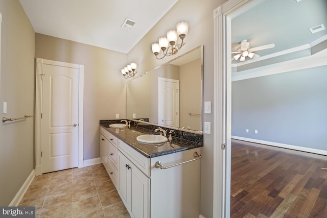 bathroom with double vanity, a sink, visible vents, and baseboards