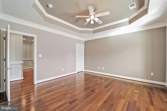 spare room with dark wood-type flooring, a raised ceiling, visible vents, and ornamental molding