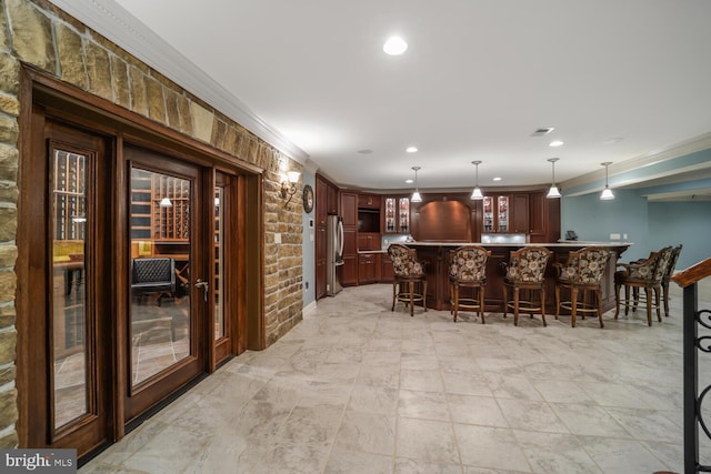 bar with recessed lighting, hanging light fixtures, ornamental molding, freestanding refrigerator, and bar